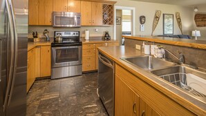 A kitchen with wooden cabinets, stainless steel appliances, a marble floor, and a large sink.
