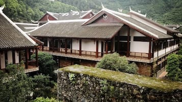 Traditional Japanese architecture with multiple buildings, stone walls, and lush greenery.