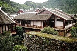 Traditionelle japanische Architektur mit mehreren Gebäuden, Steinmauern und üppiger Bepflanzung.