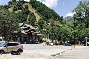 A traditional building with a curved roof, surrounded by trees and a hilly landscape.