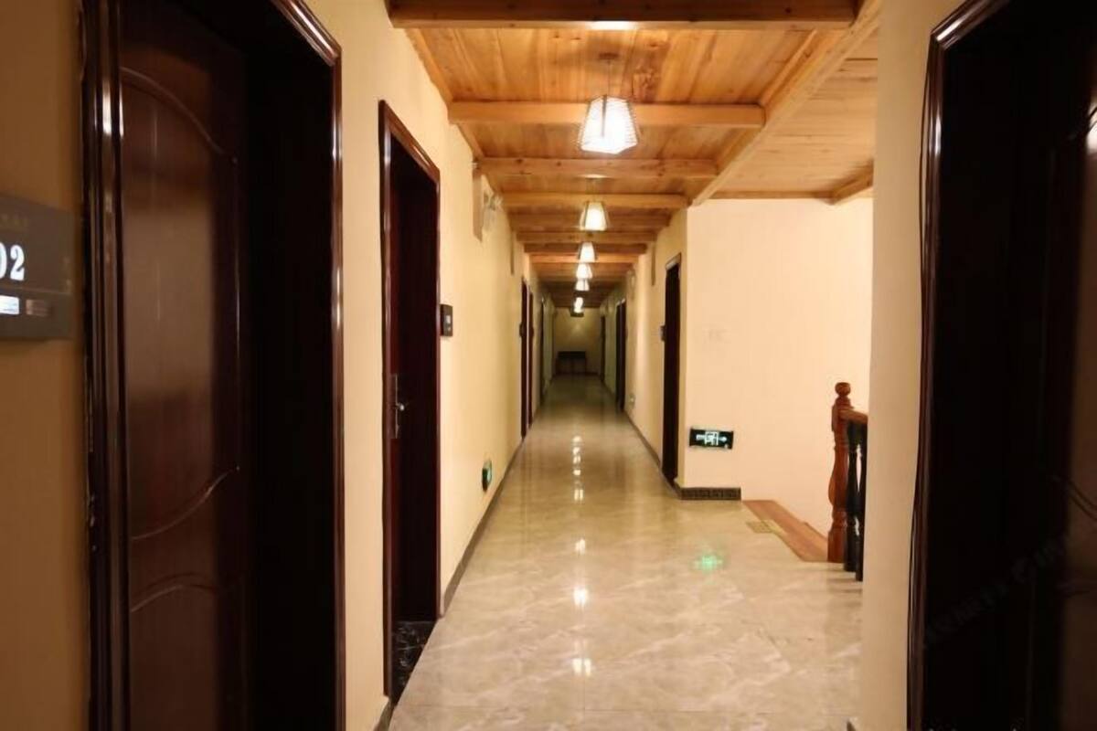 A hotel hallway with wooden ceiling, marble floors, and doors numbered 02.