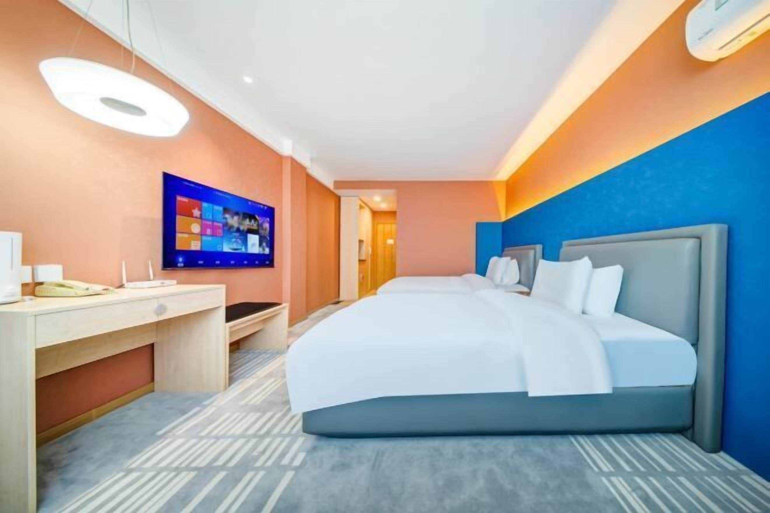 A hotel room with a bed, desk, and television.