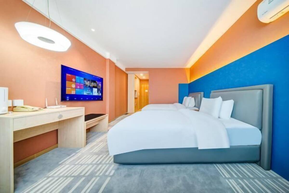 A hotel room with a bed, desk, and television.