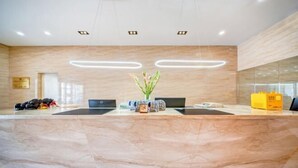 A reception desk with a marble countertop, two computers, a vase with flowers, and a yellow bag on the counter. - Lantian Hotel (Hulunbuir Ancient City) (Hulunbuir)