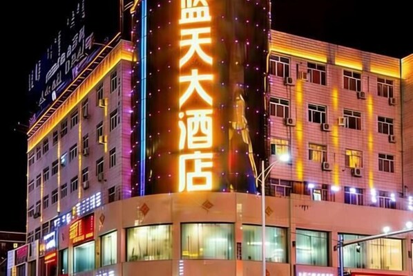 A multi-story hotel building with illuminated signage and multiple windows.