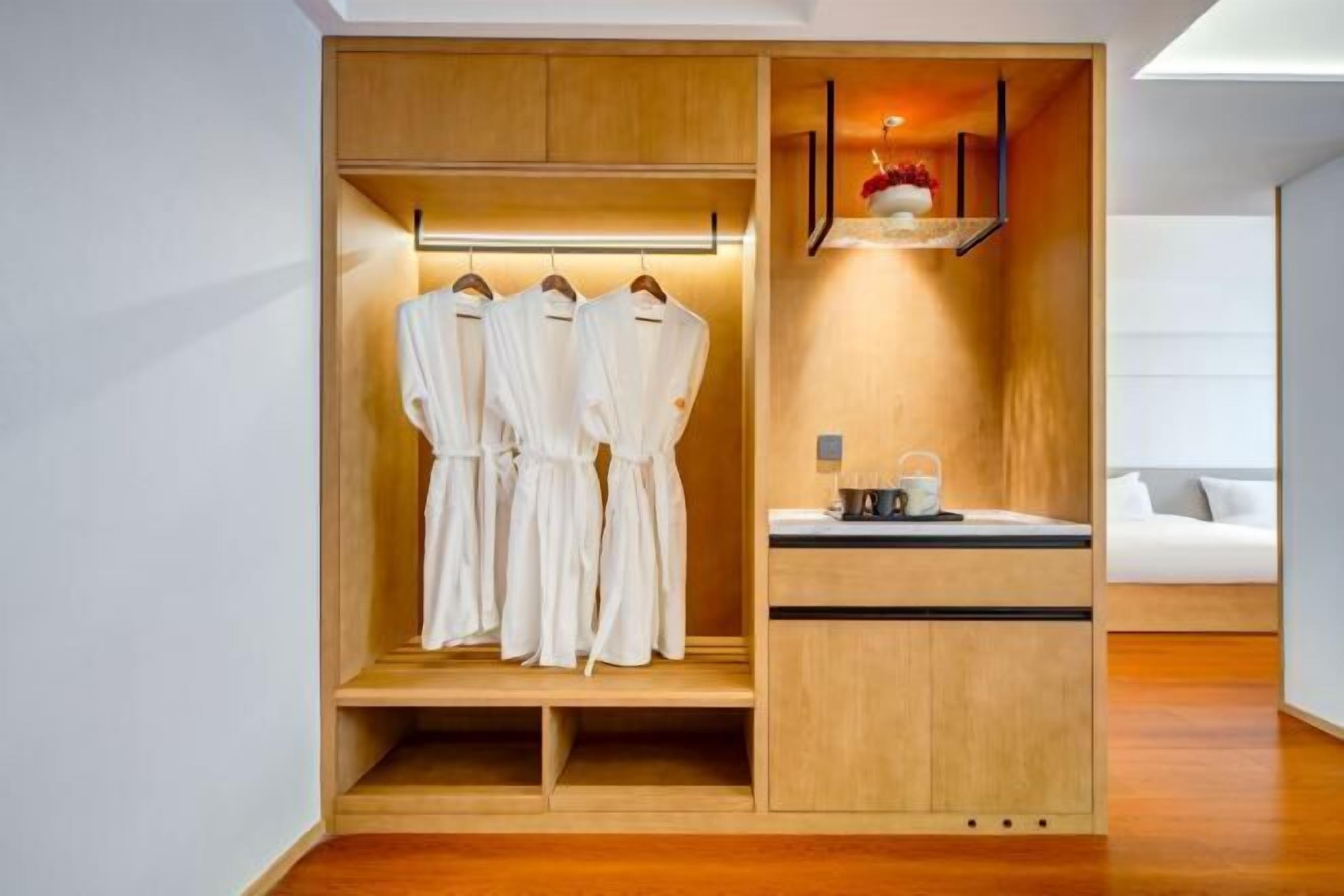 A modern room with a built-in wardrobe, a small kitchenette, and a seating area with a sofa.