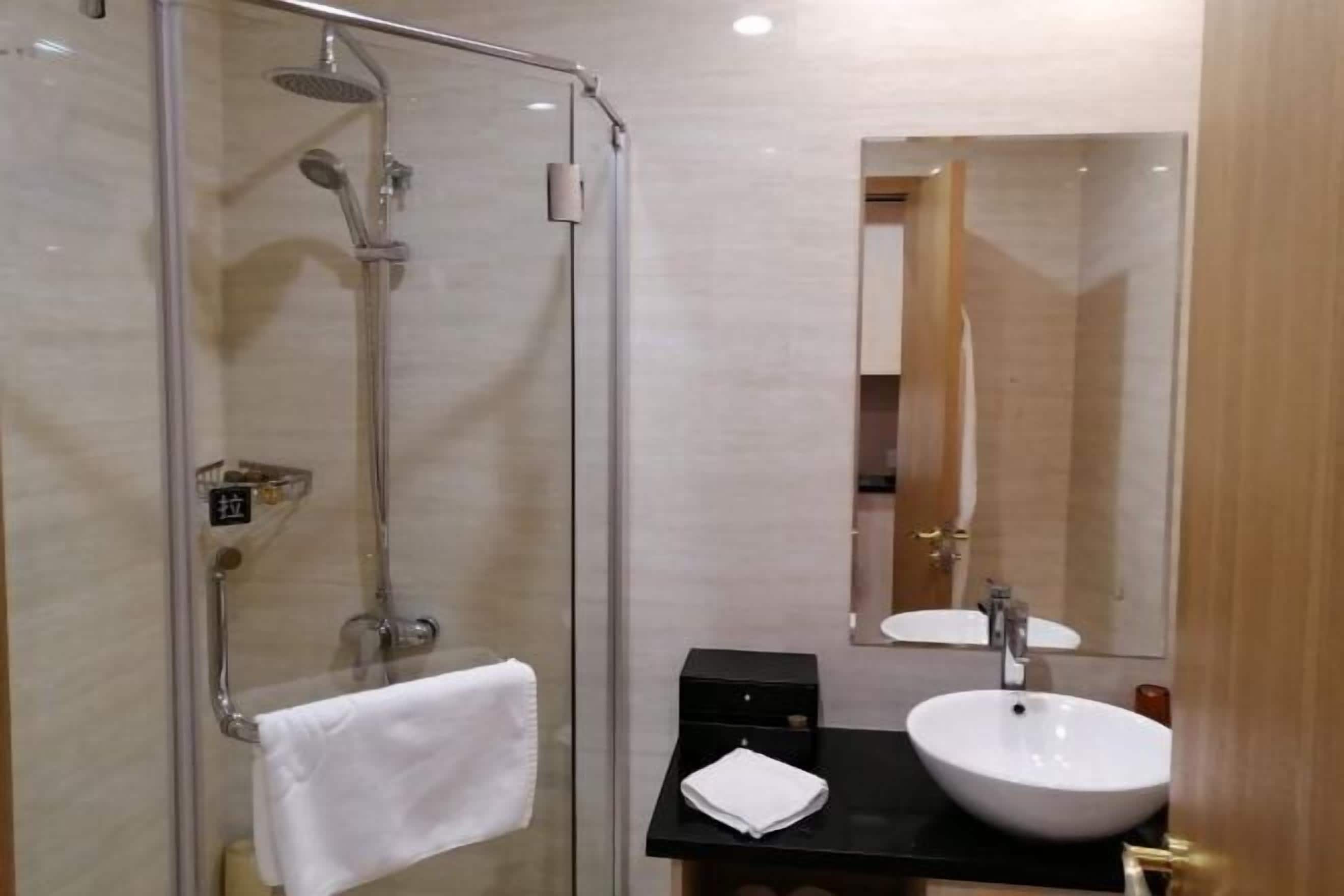 A modern bathroom with a glass shower enclosure, a white sink, and a mirror.