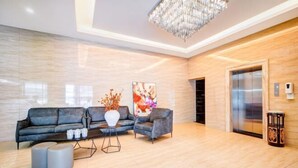A modern lobby with a grey sofa, a white vase, and a chandelier. - Lantian Hotel (Hulunbuir Ancient City) (Hulunbuir)