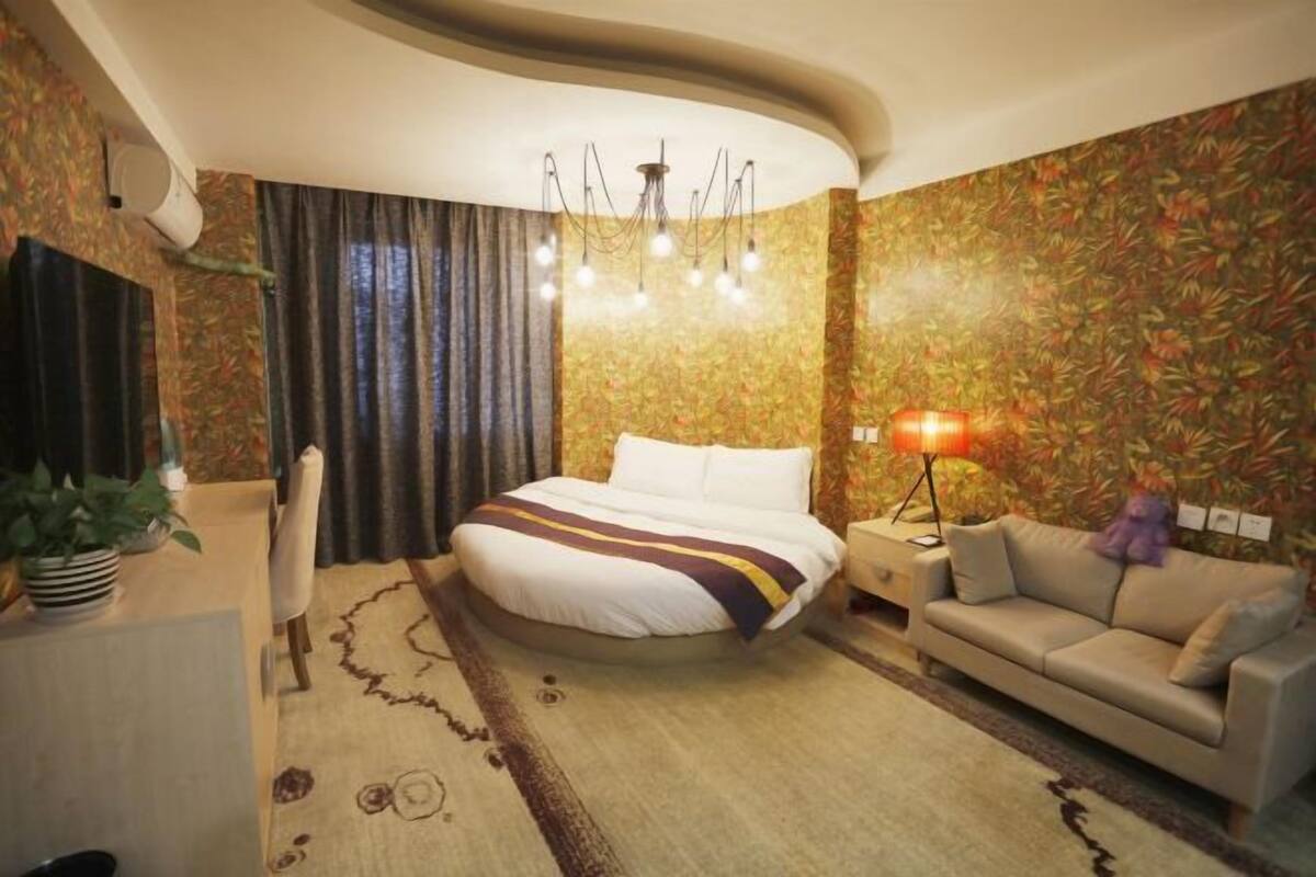 A hotel room with a large bed, a sofa, a desk, and a lamp.