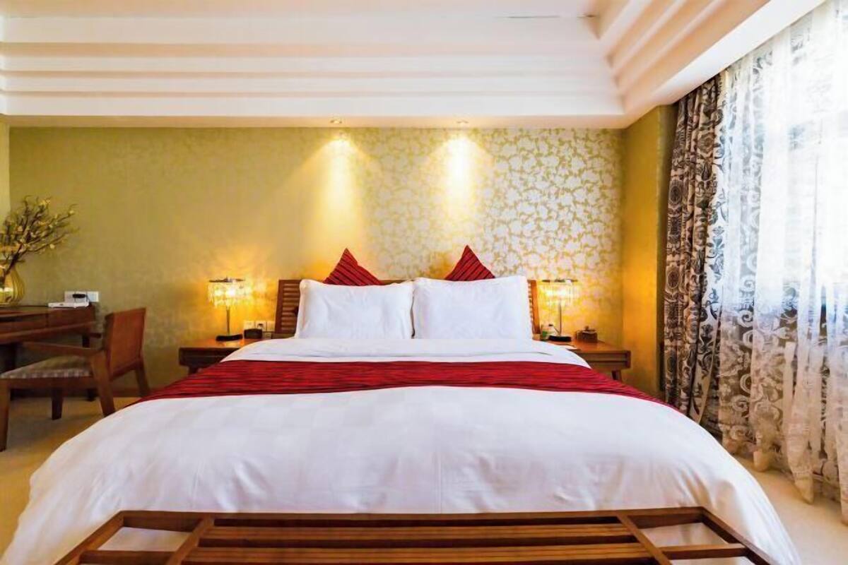 A hotel room with a bed, two bedside tables, a desk, and a chair.