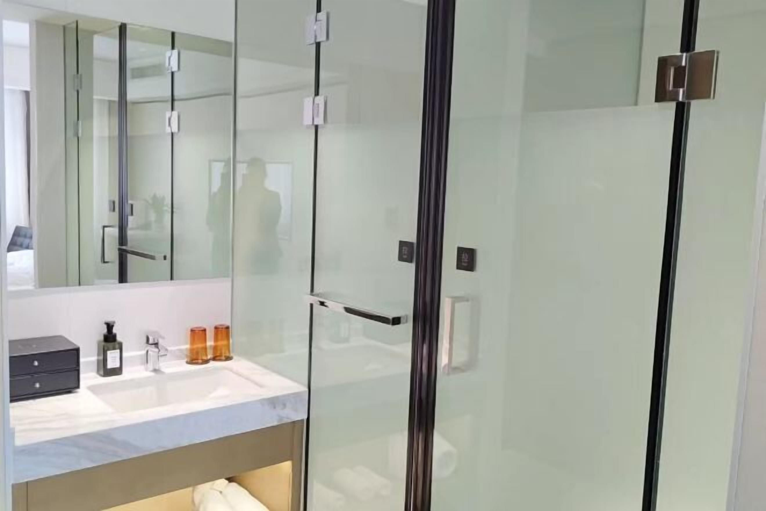 A modern bathroom with a glass shower enclosure, a vanity with a sink, and a mirror.