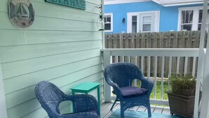 A porch with two wicker chairs and a small table, a welcome sign, and a 'Beach House' sign. - Only 2 blocks from all the action on Canal Street! (New Smyrna Beach)