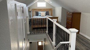 A multi-level home interior with a staircase, a bedroom with a bed, a dresser, and a window. - Only 2 blocks from all the action on Canal Street! (New Smyrna Beach)