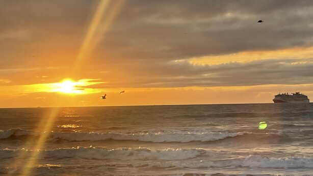 A sunset over the ocean with a ship in the distance. - Only 2 blocks from all the action on Canal Street! (New Smyrna Beach)