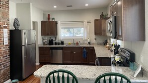 A modern kitchen with granite countertops, stainless steel appliances, and wooden cabinets. - Only 2 blocks from all the action on Canal Street! (New Smyrna Beach)