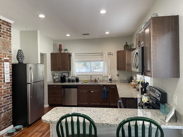 A modern kitchen with granite countertops, stainless steel appliances, and wooden cabinets.