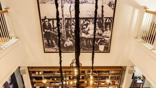 A restaurant with a central bar area, multiple seating options, and a large black-and-white photograph on the wall. - Hotel Gut Altona (Dötlingen)