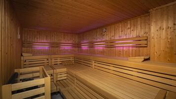 A sauna with wooden benches and benches, wooden walls, and a clock on the wall.