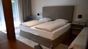 A neatly made double bed with a headboard, two bedside tables with lamps, and a chair.