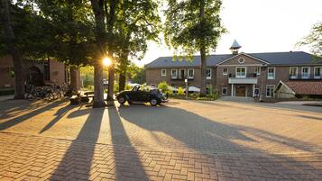 A brick building with a large driveway and a classic car parked in front.