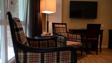 Une chambre d’hôtel avec des fauteuils à motifs écossais, un téléviseur à écran plat et une lampe.