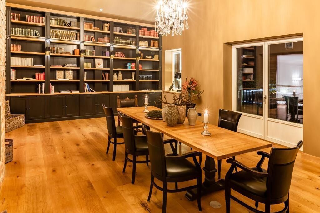 A dining area with a wooden table and chairs, surrounded by bookshelves filled with books.