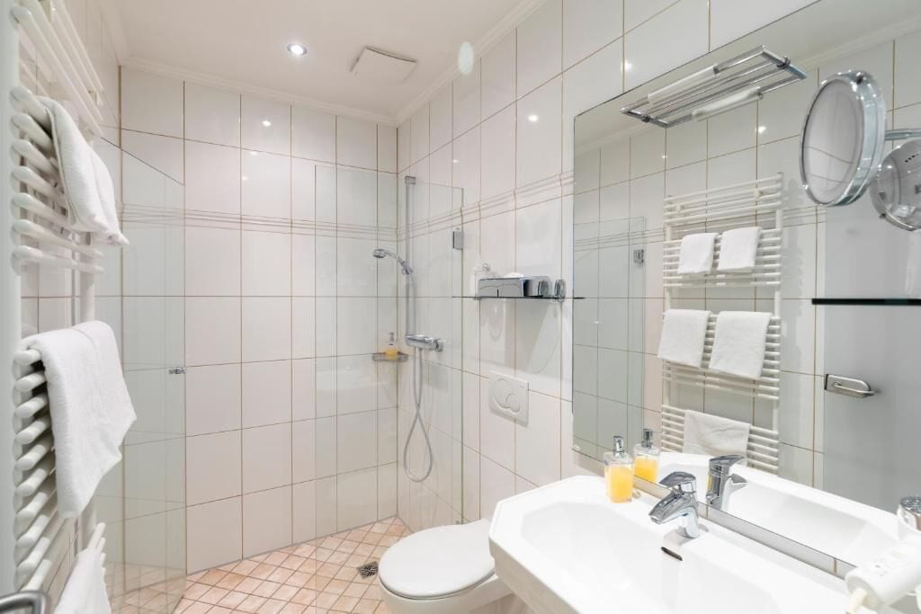Un baño moderno con cabina de ducha de vidrio, un lavabo blanco con espejo y un inodoro.