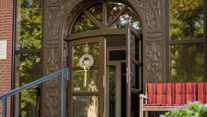A building entrance with a wrought iron gate, a bench, and a staircase leading up to the door. - Hotel Gut Altona (Dötlingen)