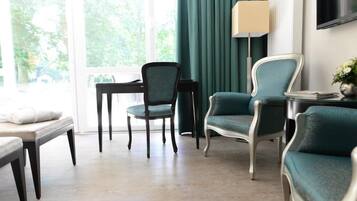 A modern room with a wooden floor, a desk with a chair, a sofa, and a lamp.