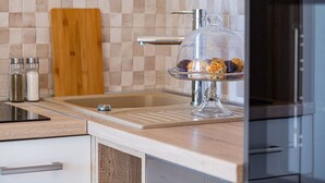A kitchen with a wooden countertop, a glass display case with baked goods, a wooden cutting board, and a tiled backsplash. - Rina Apartments - Superior One Bedroom Apartment with Terrace and Sea View (Baric Draga)