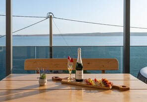 A table with a bottle of Lindermor champagne, a glass of white wine, and a wooden board with snacks. - Rina Apartments - Superior One Bedroom Apartment with Terrace and Sea View (Baric Draga)