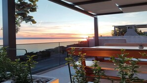 Ett modernt utomhusområde med sittplatser och utsikt över solnedgången över vattnet.
