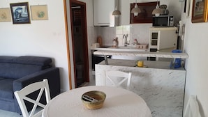 Ett kompakt bostadsutrymme med ett kök, en matplats och en soffa.