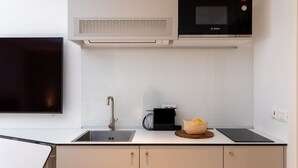 Una cuina moderna amb un microones Bosch, una cafetera i un rentaplat.