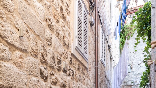 Un carreró de pedra estret amb una taula preparada per a dues persones, una banca i una escala que mena a un nivell superior.