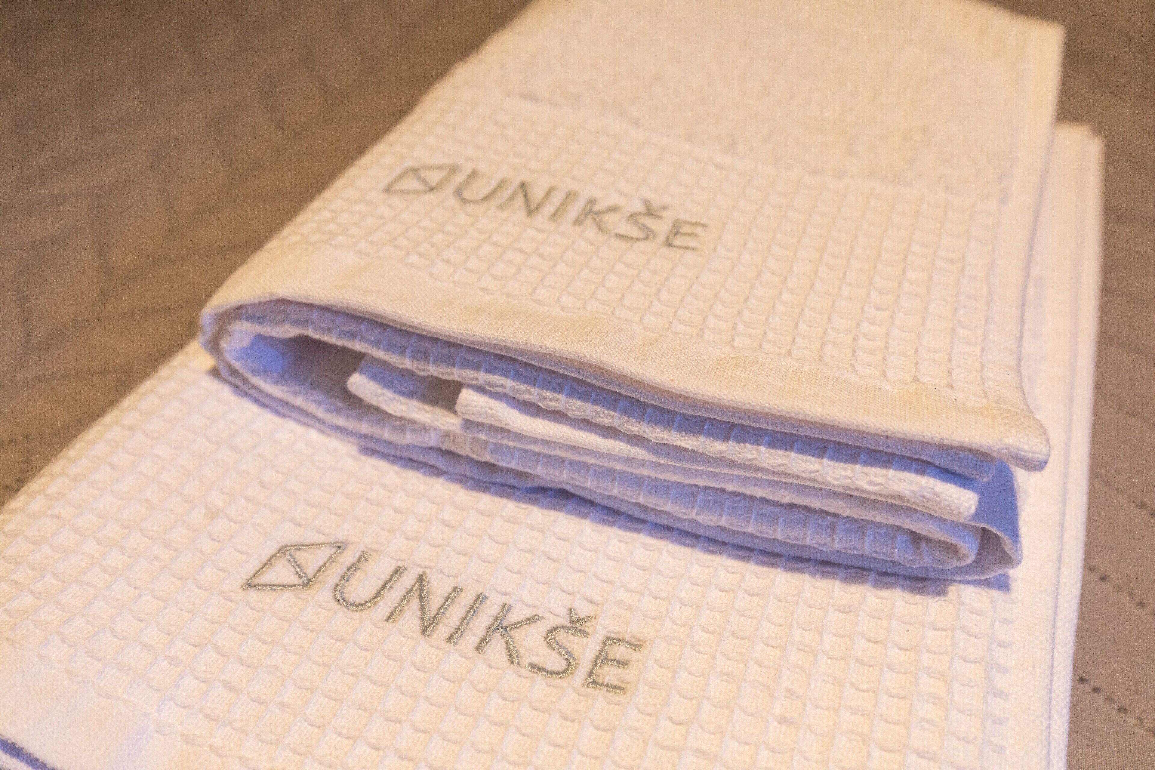 Een stapel gevouwen handdoeken met de tekst 'DUNIKŠE' in reliëf.