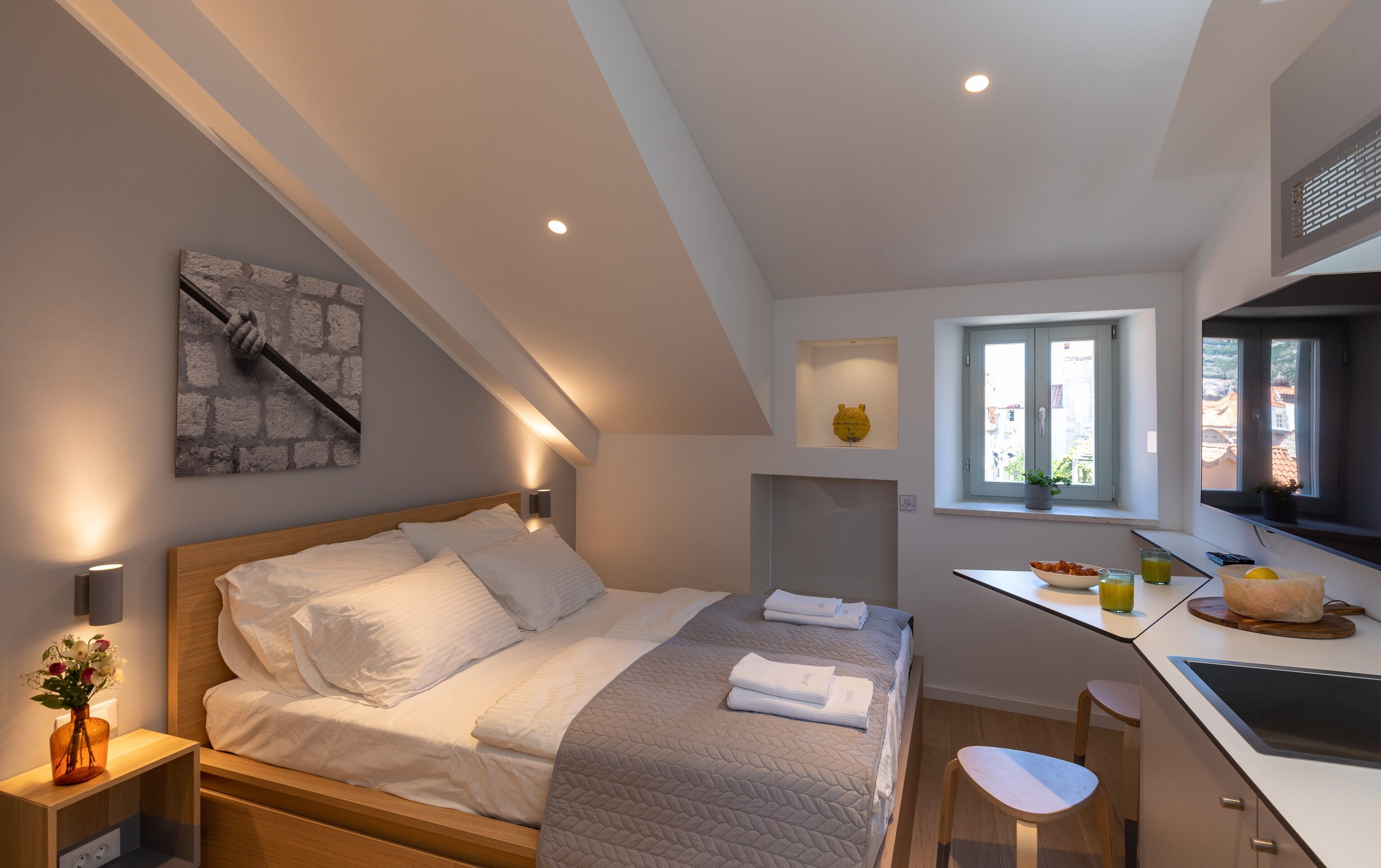 Une chambre moderne avec un lit, une table de chevet et une petite kitchenette.