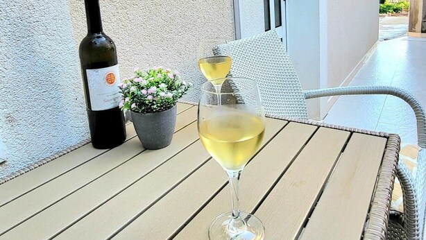 Une table avec une bouteille de vin et deux verres sur un balcon.