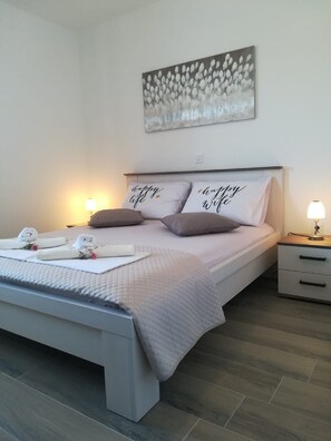 A neatly made bed with two pillows, a bedside table with a lamp, and a wall-mounted artwork. - Apartment Villa Bijele Stijene - Two Bedroom Apartment with Terrace and Sea View (Karlobag)