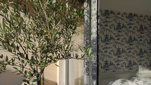 Una habitación con una cama, un ventanal con vistas a un árbol y una pared con un diseño azul.