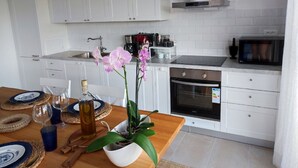 Una cocina moderna con armarios blancos, una campana de acero inoxidable y un microondas.