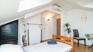 Un dormitorio con cama de madera, ventilador de techo, planta en maceta y un atrapasueños en la pared.