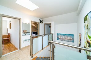 Un interior moderno con una escalera, un comedor y obras de arte en las paredes.