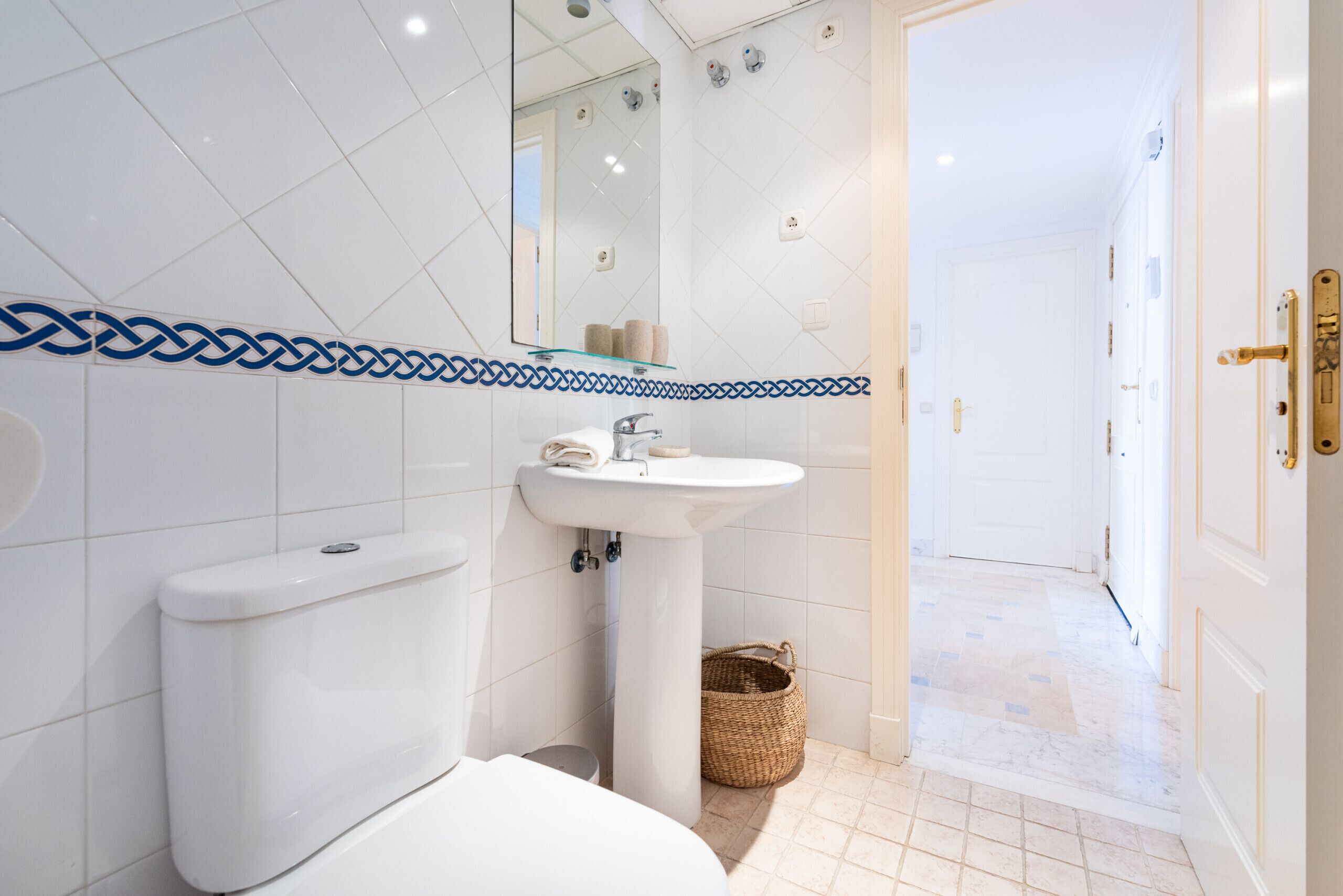 A modern bathroom with a white toilet, a pedestal sink, and a glass shower enclosure.
