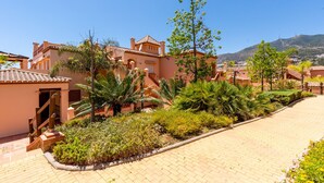 A residential area with a paved driveway, palm trees, and a building with a tiled roof. - Resort Mediterra II | Apartment with Sea View (Benalmádena)