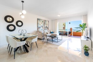A modern living room with a dining area, a sofa set, and a balcony with a view.