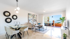 A modern living room with a dining area, a sofa set, and a balcony with a view. - Resort Mediterra II | Apartment with Sea View (Benalmádena)
