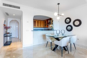 Une cuisine moderne avec des meubles en bois, une table à manger en verre et des chaises blanches.