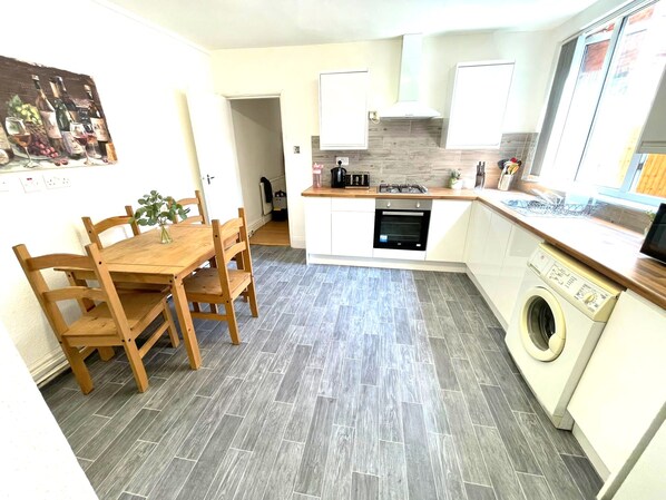 A compact kitchen with a dining area, a washing machine, and a small dining table with chairs.
