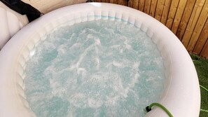 An inflatable hot tub with water bubbling, surrounded by a wooden fence.